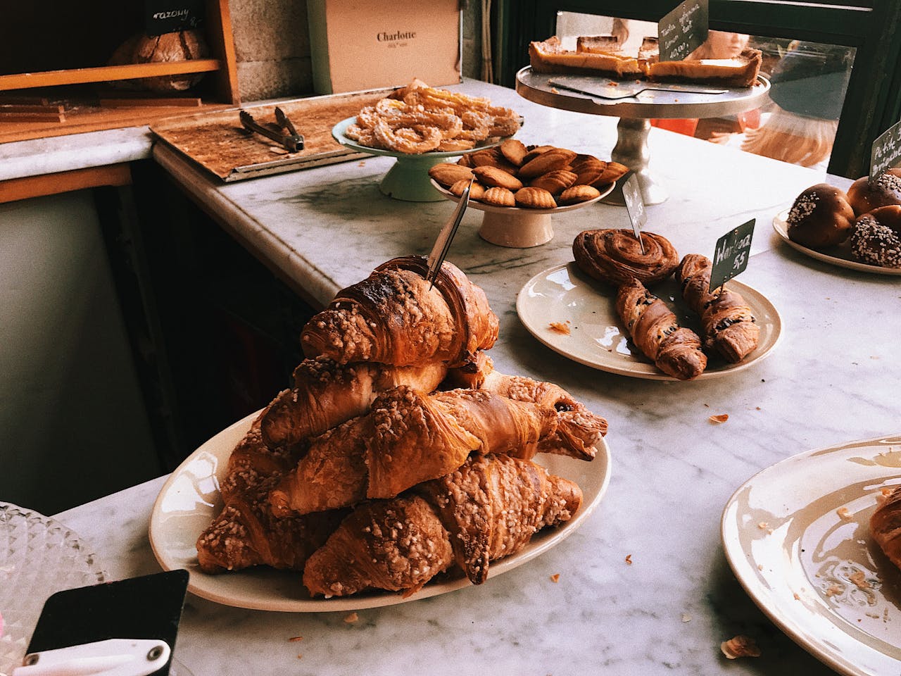 gallery-6 A tempting assortment of croissants and pastries on a marble countertop, perfect for a bakery theme.